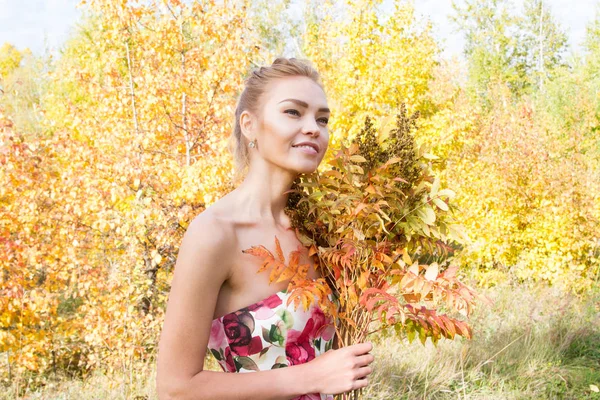 Ormanda yürüyüş kız bir buket sarı sonbahar yaprakları