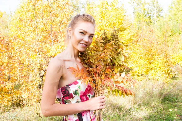 Ormanda yürüyüş kız bir buket sarı sonbahar yaprakları