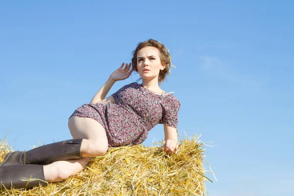 Girl lies in the field on a straw bale — Stock Photo, Image