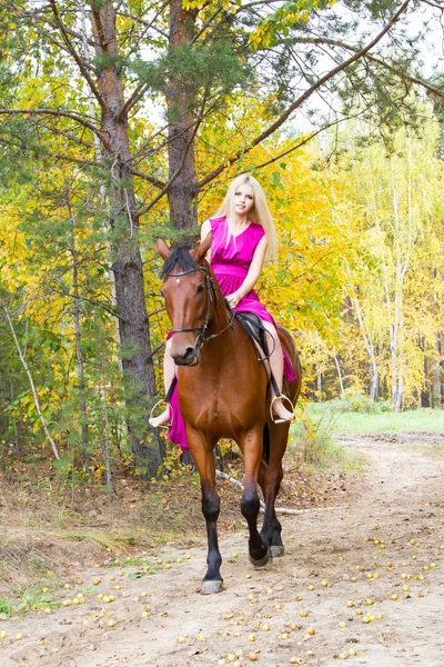 Blonde riding a horse in an autumn forest — Stock Photo, Image