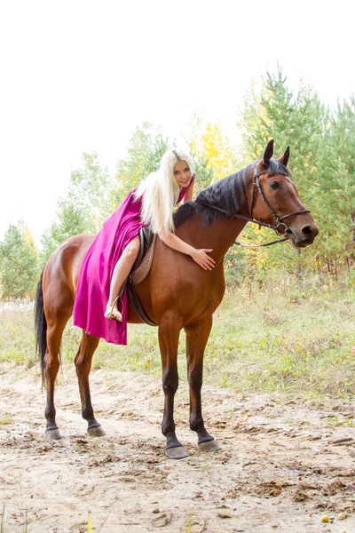 Blondine reitet in einem herbstlichen Wald — Stockfoto