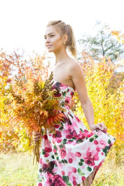 Sarı yapraklar ormanda yürüyüş bir buket ile genç kız