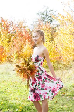 Sarı yapraklar ormanda yürüyüş bir buket ile genç kız