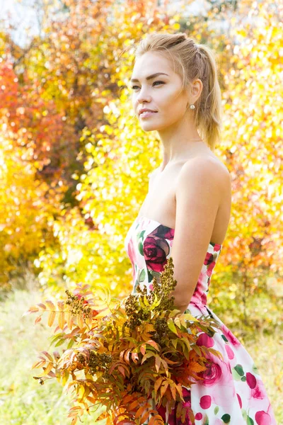 Chica joven con un ramo de hojas amarillas caminando en el bosque —  Fotos de Stock