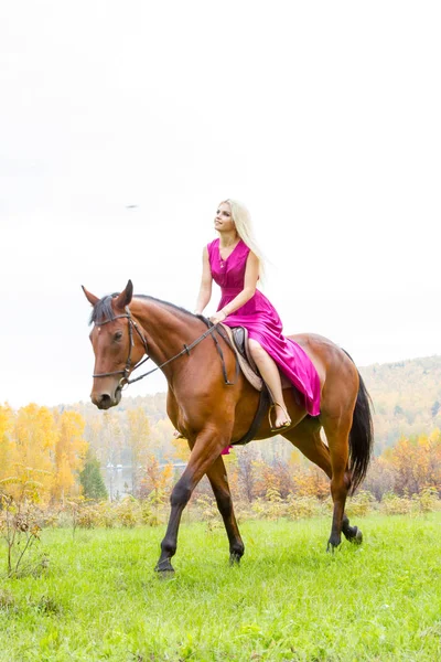 Loira em um vestido de noite monta um cavalo — Fotografia de Stock