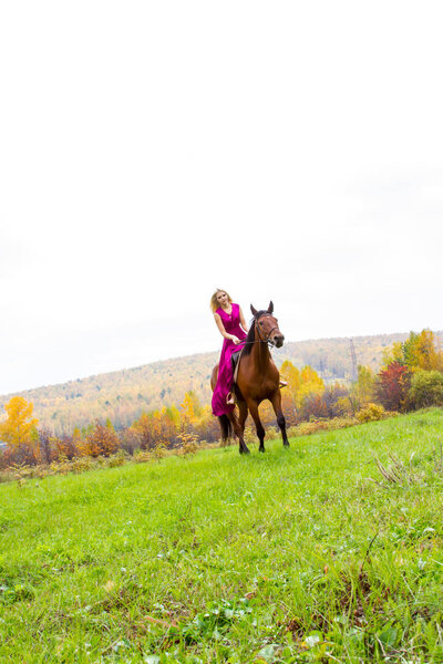 blonde in an evening dress rides a horse