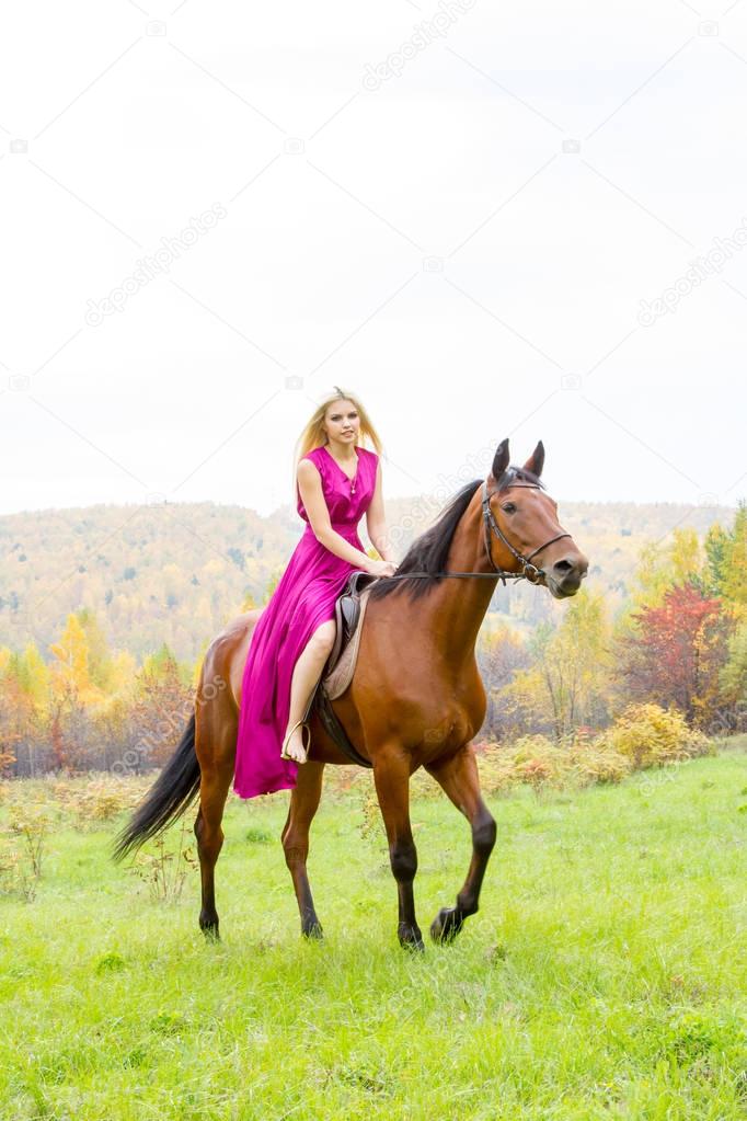 blonde in an evening dress rides a horse