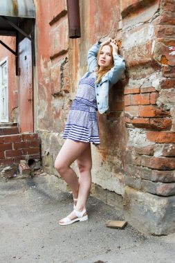 kısa etekli kız eski bir ev tuğla duvar tarafından duruyor