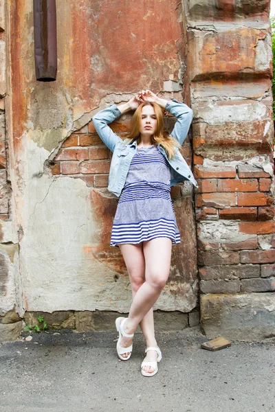 Девушка в короткой юбке стоит у кирпичной стены старого дома — стоковое фото