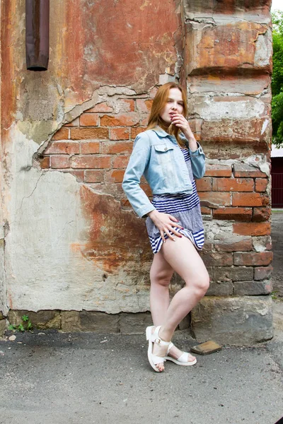 kısa etekli kız eski bir ev tuğla duvar tarafından duruyor