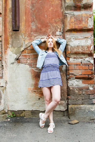kısa etekli kız eski bir ev tuğla duvar tarafından duruyor