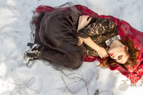 Mädchen mit hellem Make-up liegt im Schnee — Stockfoto