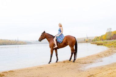 Genç sarışın bir binicilik Körfezi kıyı atlar