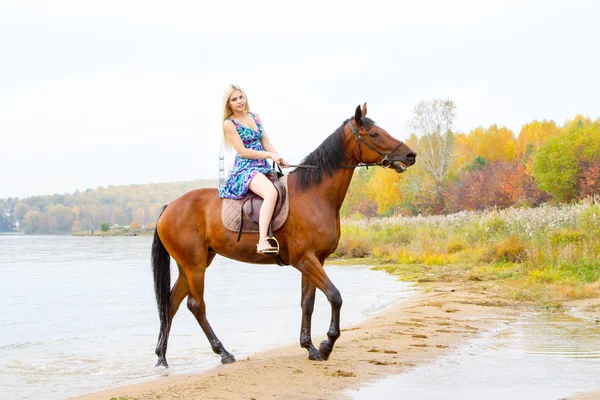 Молода блондинка їде на коні стрибає уздовж берега затоки — стокове фото