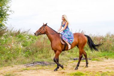 Genç sarışın bir binicilik Körfezi kıyı atlar