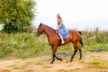 Genç sarışın bir binicilik Körfezi kıyı atlar