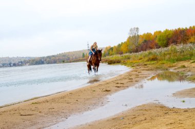 Genç sarışın bir binicilik Körfezi kıyı atlar