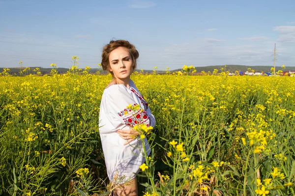 Ragazza in camicia ricamata tra i campi fioriti — Foto Stock