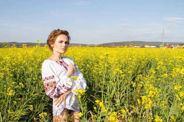 Ragazza in camicia ricamata tra i campi fioriti — Foto Stock