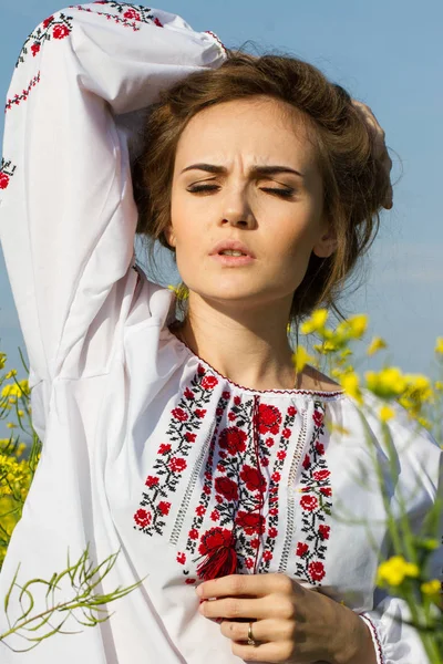 Chica en una camisa bordada entre el campo floreciente —  Fotos de Stock