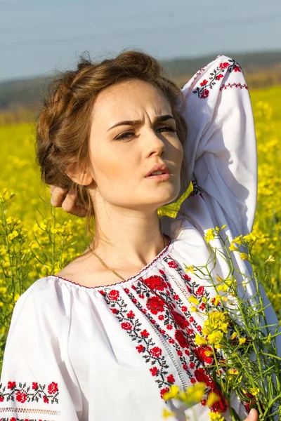 Flicka i en broderad skjorta bland blommande området — Stockfoto