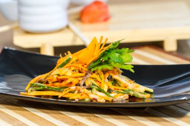 Üzerinde siyah bir tabak deniz ürünleri ile sebze salatası