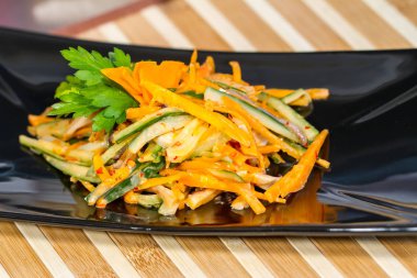 Üzerinde siyah bir tabak deniz ürünleri ile sebze salatası