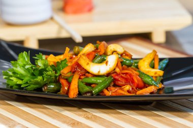 Üzerinde siyah bir tabak deniz ürünleri ile sebze salatası