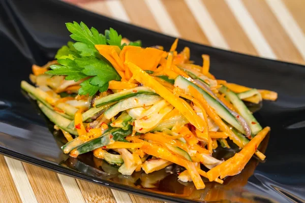 Üzerinde siyah bir tabak deniz ürünleri ile sebze salatası