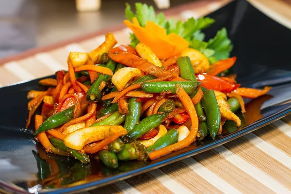 Üzerinde siyah bir tabak deniz ürünleri ile sebze salatası