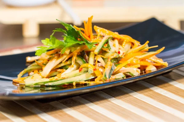 Üzerinde siyah bir tabak deniz ürünleri ile sebze salatası