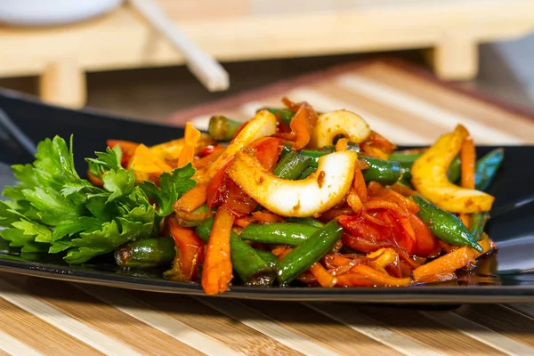 Üzerinde siyah bir tabak deniz ürünleri ile sebze salatası