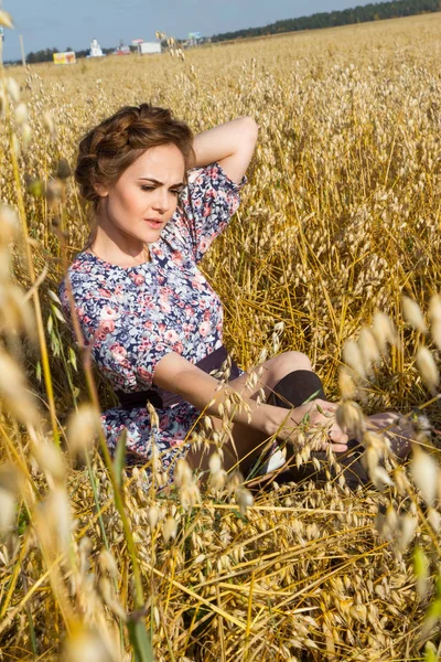 Chłopska dziewczyna siedzi w polu wśród dojrzałych uszy — Zdjęcie stockowe