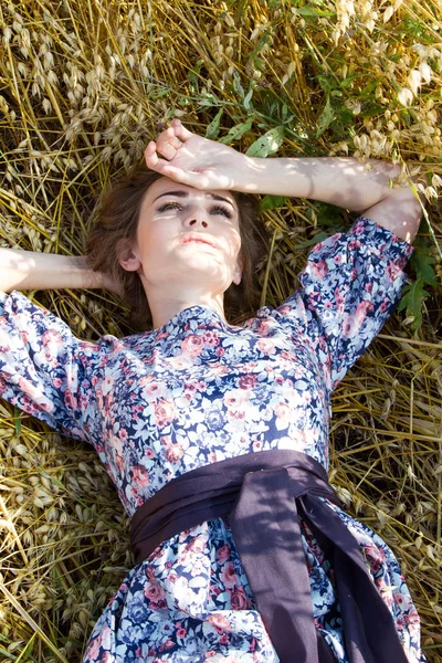 Ung bonde kvinnan ligger på ett fält mellan öronen av havre — Stockfoto