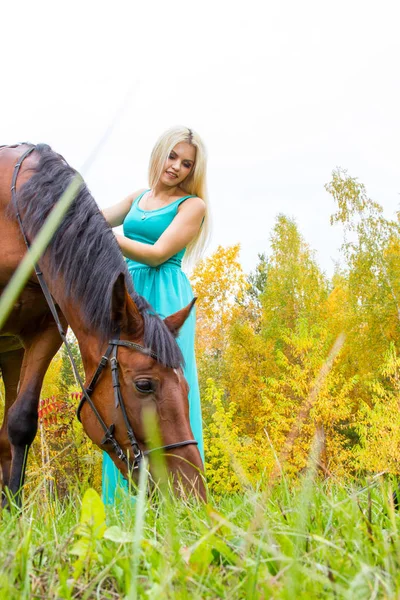 Дівчина з конем, що йде в осінньому лісі — стокове фото
