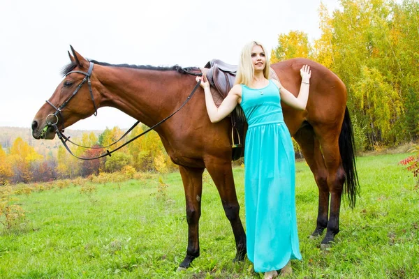 Mädchen mit einem Pferd, das im herbstlichen Wald spaziert — Stockfoto
