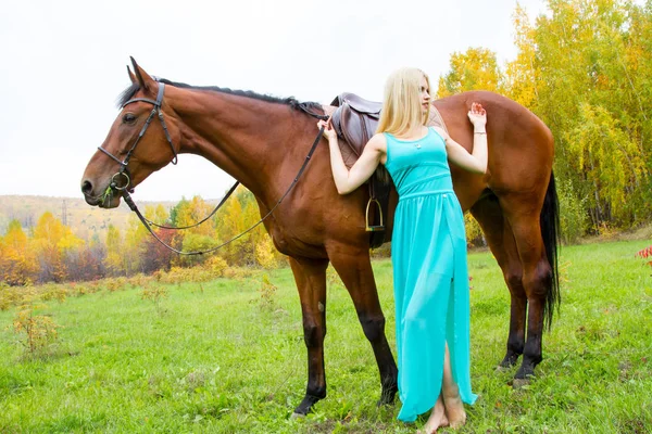 Дівчина з конем, що йде в осінньому лісі — стокове фото