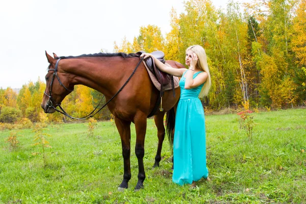 Flicka med en häst som går i en höst-skog — Stockfoto