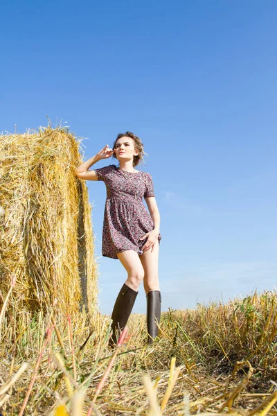 Dívka stojící v poli poblíž balík slámy — Stock fotografie