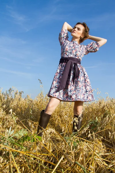 Девушка стоит в поле против голубого безоблачного неба — стоковое фото