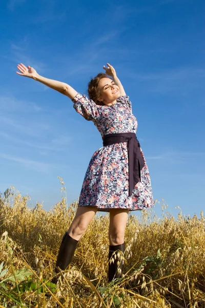 Chica de pie en el campo contra el cielo azul sin nubes —  Fotos de Stock