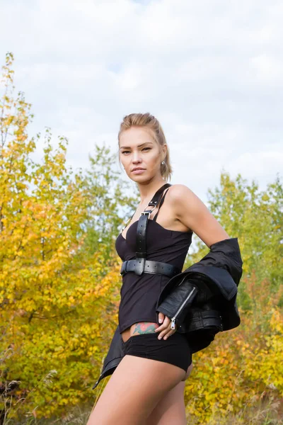 Sexy Genç kız bir deri ceket ve mühimmat sonbahar yaprakları arasında