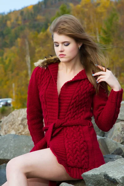 Ung flicka i en röd kofta mot bakgrund av hösten lämnar — Stockfoto