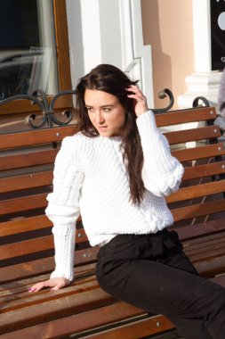 Bir banka Binası arka plan üzerinde beyaz kazaklı genç kız oturur