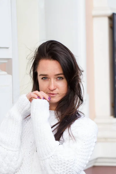 Chica joven en suéter blanco se sienta en el fondo del edificio — Foto de Stock