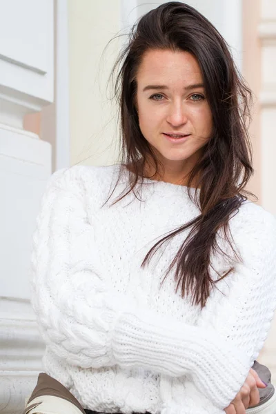 Fiatal lány az építési háttér fehér pulóver — Stock Fotó
