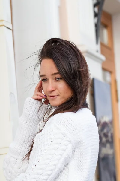 Młoda dziewczyna w biały sweter na tle budynku — Zdjęcie stockowe