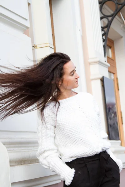 Jeune fille en pull blanc sur fond de bâtiment — Photo