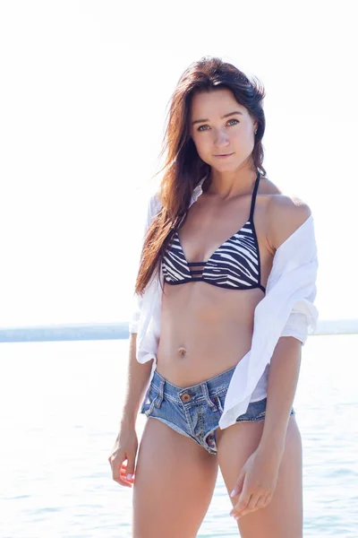 白いシャツに短いデニムのショート パンツでビーチで女の子 — ストック写真