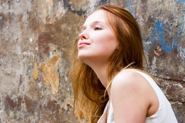 Kızıl saçlı kız dökük bir eski püskü duvara karşı